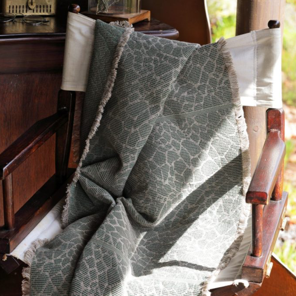 Textured blanket draped over a wooden chair with a blurred background