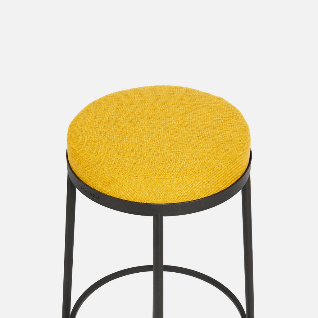 A locally made kitchen stool made from powder-coated steel and upholstered in bright yellow fabric from Hertex