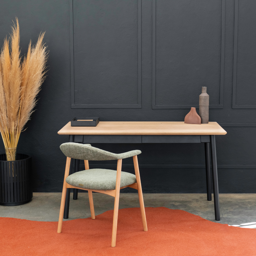 Wooden desk with chair against a dark wall with decorative elements.