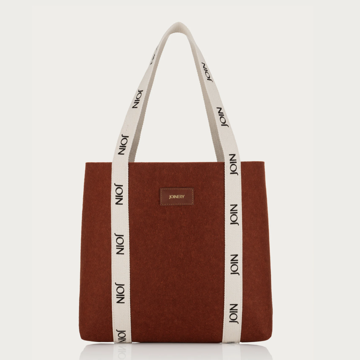 Brown tote bag with white handles featuring 'JOIN' branding on a white background