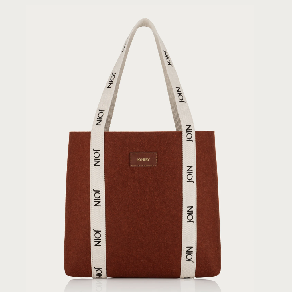 Brown tote bag with white handles featuring 'JOIN' branding on a white background
