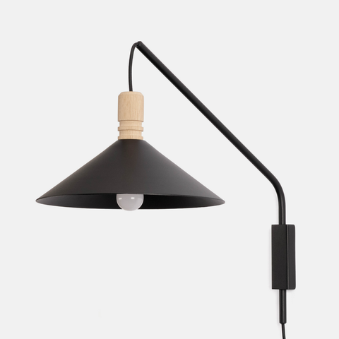A modern black metal wall sconce lamp with a conical shade, adjustable curved arm, light natural oak accent, and visible bulb, shown against a plain light gray background.