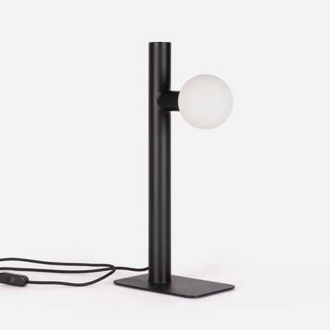 Modern black table lamp with a white globe light on a white background