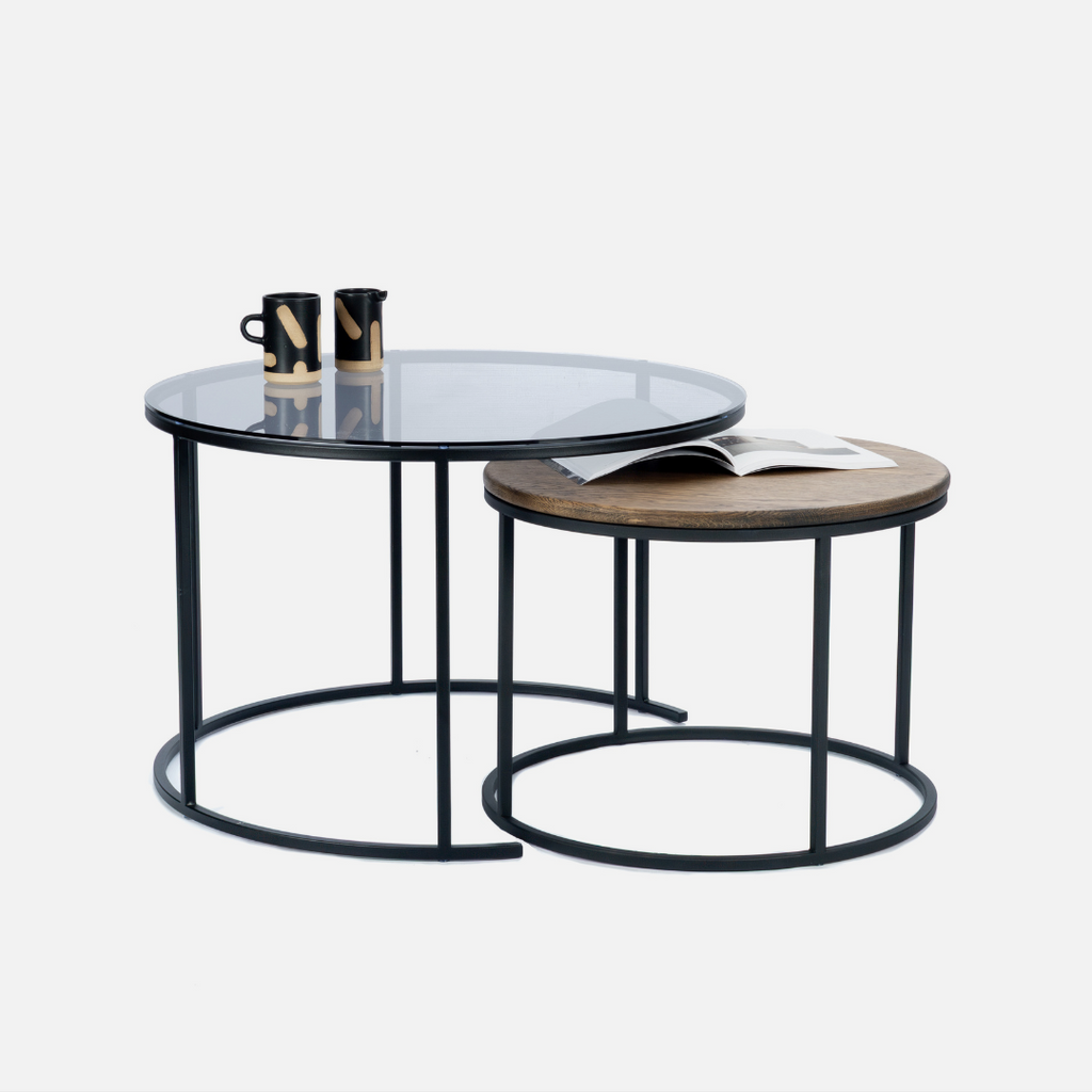 Set of two round coffee tables with glass top and wooden bottom on a white background