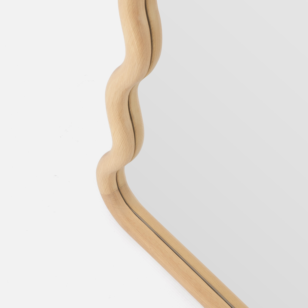 Wooden-framed mirror with wavy design on a white background