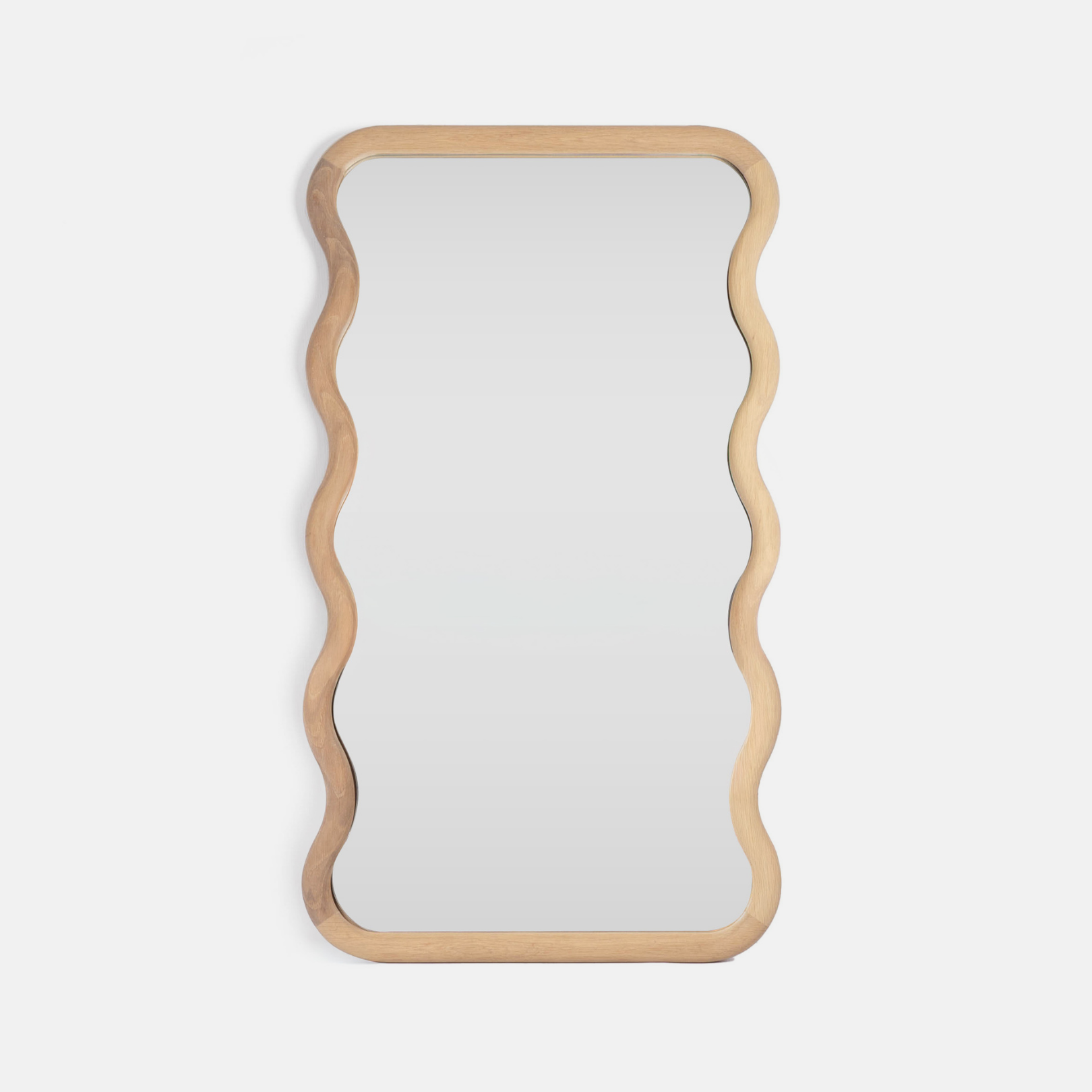 A solid oak vanity mirror with a wavy edge design on a light grey background