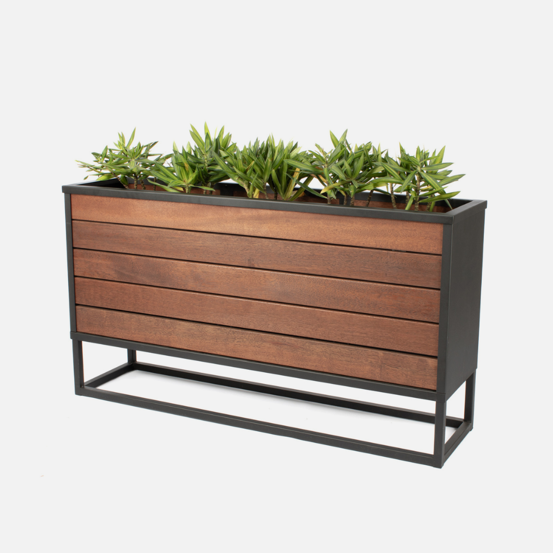 A large rectangular Stable Box Planter with powder-coated steel frame and Keruing hardwood slats, containing green plants, designed for outdoor use.