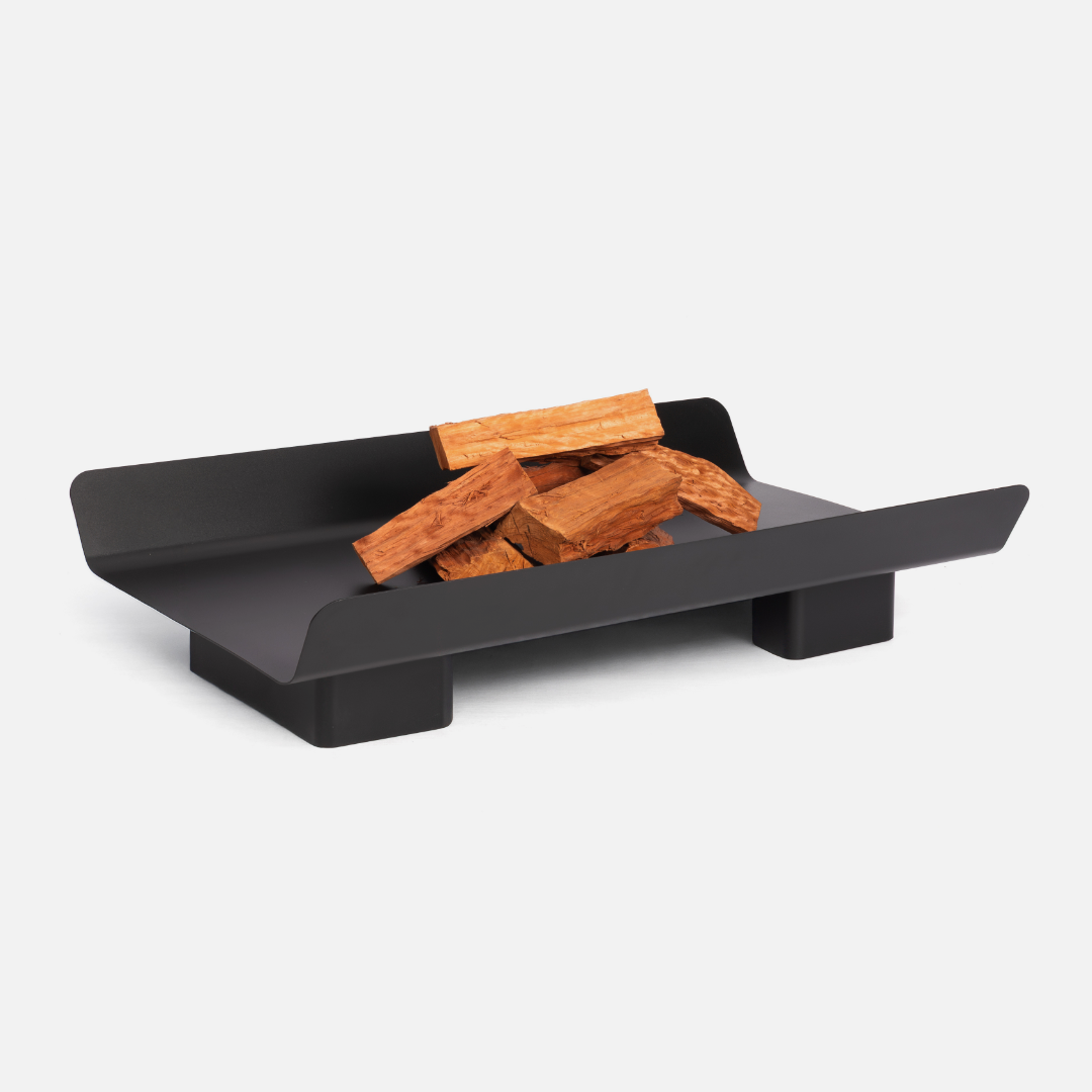 Black metal fire pit with wooden logs on a white background