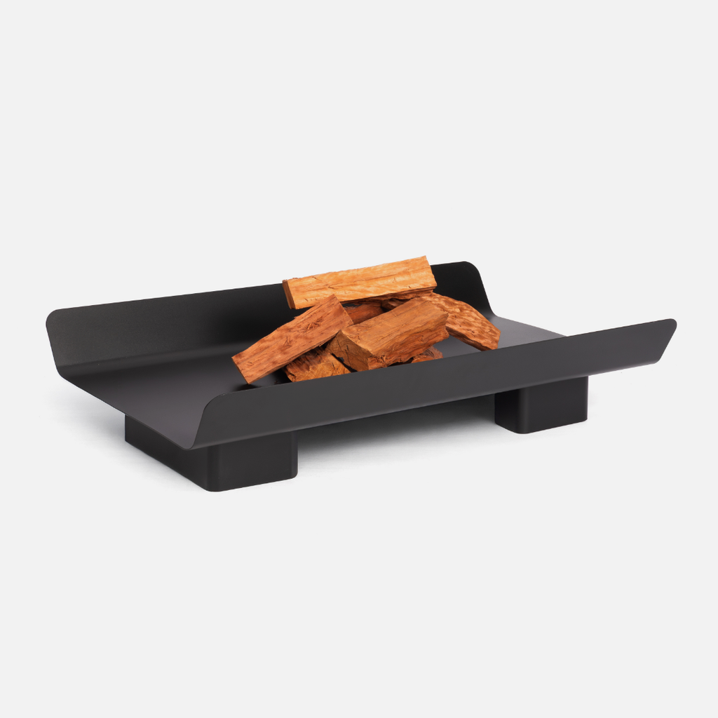 Black metal fire pit with wooden logs on a white background